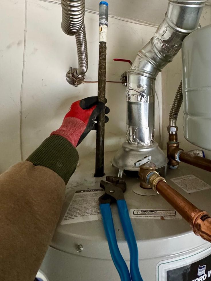 Plumber replacing a sacrificial anode rod on a water heater